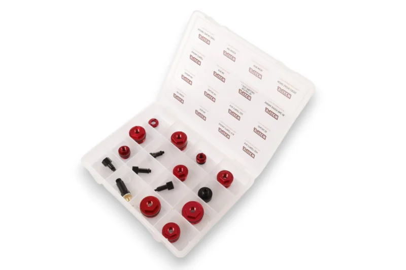 Red anodized metal fittings organized in a clear plastic storage case with individually divided compartments, likely a tool kit set.